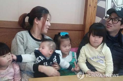 Kang Mi-ok holds her fourth baby as she talks with her husband at a cafe in Cheongyang, 160 kilometers south of Seoul, on Jan. 7, 2017. (Yonhap)
