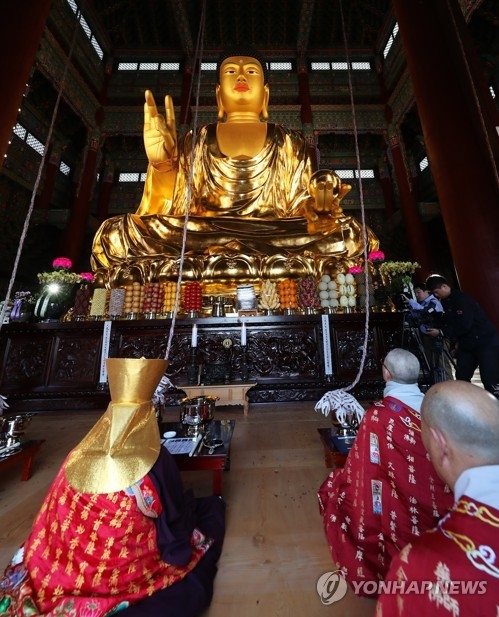 Buddhist monks hold a rite in front of a bronze statue of "Maitreya" Buddha at Daegwang Temple in Seongnam, just south of Seoul, on April 10, 2017, to mark the dedication of a new hall containing the Buddha statue after a 14-year construction project. (Yonhap)