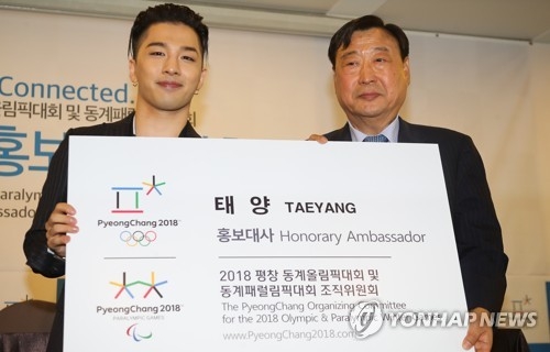 BIGBANG's Taeyang (L) holds up a card showing him as an honorary ambassador for the 2018 PyeongChang Winter Olympics, alongside Lee Hee-beom, head of PyeongChang's organizing committee, at a ceremony in Seoul on June 21, 2017. (Yonhap)