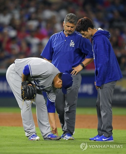 In this photo taken by the Associated Press on June 28, 2017, Los Angeles Dodgers' South Korean pitcher Ryu Hyun-jin (L) points to his foot as a trainer (C) and his interpreter (R) watch him after he was struck by a comebacker hit by Los Angeles Angels' Andrelton Simmons. (Yonhap)