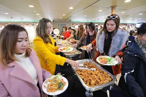 Tourists put food on their plates at a buffet on a cruise ship. (Yonhap) 