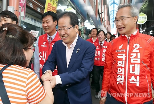 Hong Joon-pyo, chief of the main opposition Liberty Korea Party (LKP), shakes hands with a citizen during his visit to a local market in Busan on June 9, 2018. (Yonhap)