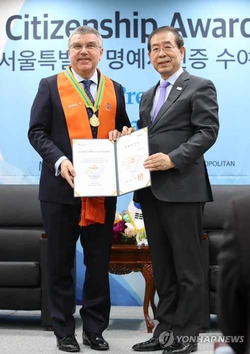 IOC President Thomas Bach (L) poses for a photo with Seoul Mayor Park Won-soon after receiving an honorary citizenship certificate at the Seoul City Hall on March 8, 2018, in this file photo. (Yonhap)