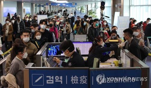 People wearing masks wait in line to pass the quarantine checkpoint at Incheon International Airport, west of Seoul, on Jan. 29, 2020. (Yonhap)