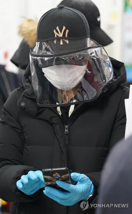 A foreign resident wearing a face mask and a hat with a face shield waits at an immigration office in Seoul on March 6, 2020, to apply for voluntary departure from the country amid concern about the spread of the new coronavirus. (Yonhap)