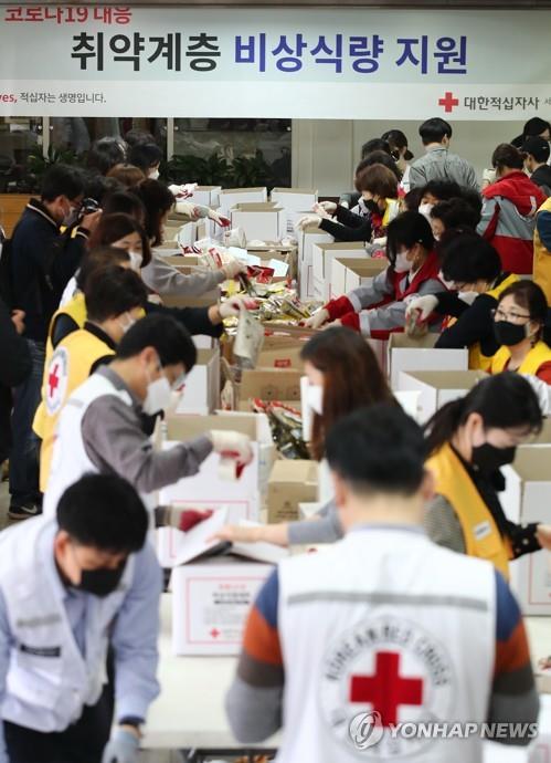 Volunteers prepare emergency relief kits packed with basic necessities like instant food at an office of the National Red Cross in Seoul on March 27, 2020, for delivery to impoverished people experiencing difficulties amid the spread of the new coronavirus. (Yonhap)