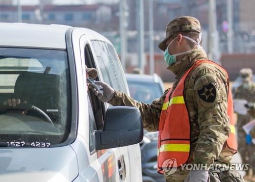 A military guard at U.S. Army Garrison Humphreys in Pyeongtaek, 70 kilometers south of Seoul, checks the temperature of a driver to screen entrants to the compound for the novel coronavirus on Feb. 28, 2020, in this photo provided by the United States Forces Korea. (PHOTO NOT FOR SALE) (Yonhap)