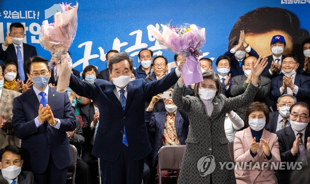 Lee Nak-yon (L), the ruling Democratic Party's parliamentary candidate for Seoul's Jongno constituency, raises up bouquets of flowers in his election office with his wife to celebrate his election win on April 15, 2020. (Yonhap)