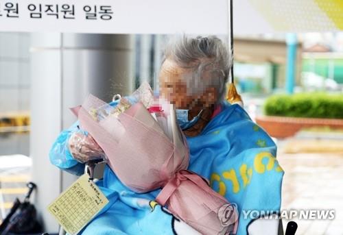 A 104-year-old woman, South Korea's oldest coronavirus patient, receives flowers after being discharged from Pohang Medical Center in Pohang on May 15, 2020. (Yonhap)