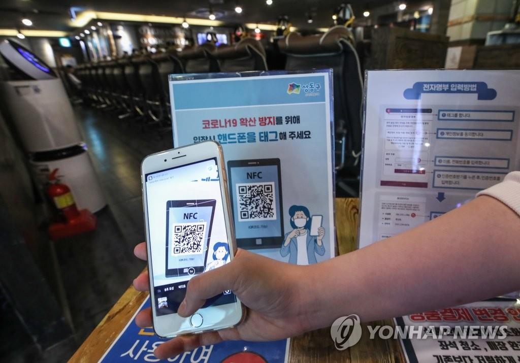An employee at an internet cafe in Seoul demonstrates the scanning of a patron's quick response (QR) code on June 1, 2020. (Yonhap) 