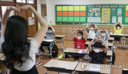 Students exchange greetings with their teacher while seating in a zigzag arrangement at Samsung Elementary School in Gimhae, 449 kilometers southeast of Seoul, on June 3, 2020, when South Korea implemented the third phase of school reopening for high school first-graders, middle school second-graders and elementary school third- and fourth-graders. (Yonhap)