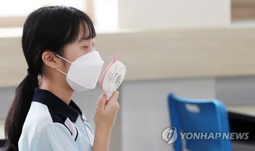 A student cools herself with a hand-held fan inside a classroom in Chuncheon, Gangwon Province, on June 8, 2020. (Yonhap) 