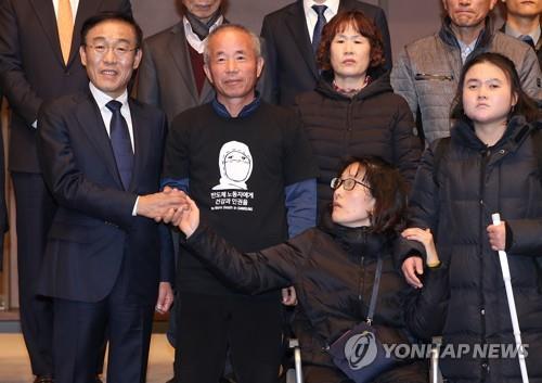 In this photo, taken on Nov. 23, 2018, Samsung Electronics CEO Kim Ki-nam (L) poses for a photo with victims of work-related diseases after signing a compensation agreement in Seoul. (Yonhap)