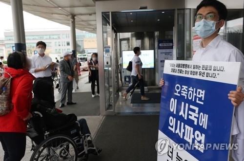 A trainee doctor at Seoul National University Hospital in downtown Seoul holds a sign denouncing the government's medical reform plan, on Sept. 2, 2020. (Yonhap) 