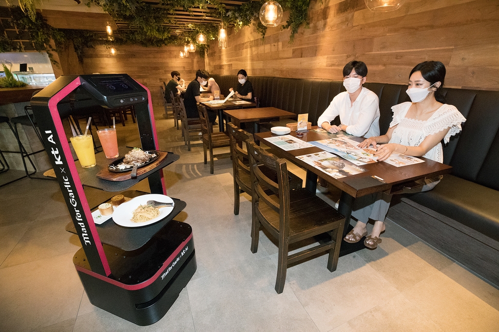 KT Corp.'s artificial intelligence-powered robot takes food and drinks to a table at a Mad for Garlic restaurant in southern Seoul, in this photo provided by the company on Sept. 1, 2020. (PHOTO NOT FOR SALE) (Yonhap)