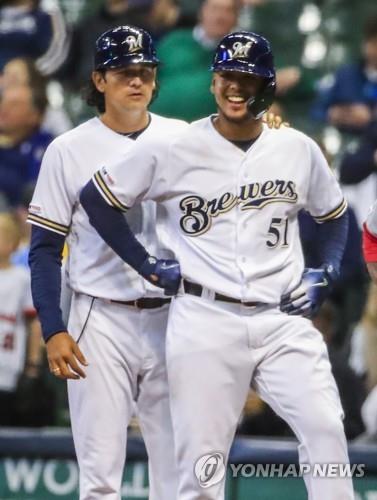 In this EPA file photo from May 7, 2019, Milwaukee Brewers' first base coach Carlos Subero (L) stands near the bag next to the team's starting pitcher Freddy Peralta after Peralta's single in the bottom of the fifth inning of a Major League Baseball regular season game against the Washington Nationals at Miller Park in Milwaukee. (Yonhap)