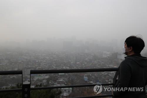 A man looks at the sky of Seoul thick with yellow dust from an observatory of Mount Inwang on March 29, 2021. (Yonhap)