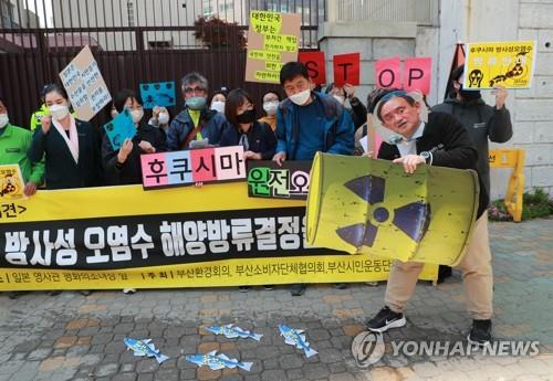 A protestor wearing a mask depicting Japanese Prime Minister Yoshihide Suga simulates the disposal of radioactive water into the ocean during a rally in front of the Japanese Consulate in the southeastern port city of Busan on April 14, 2021. (Yonhap)