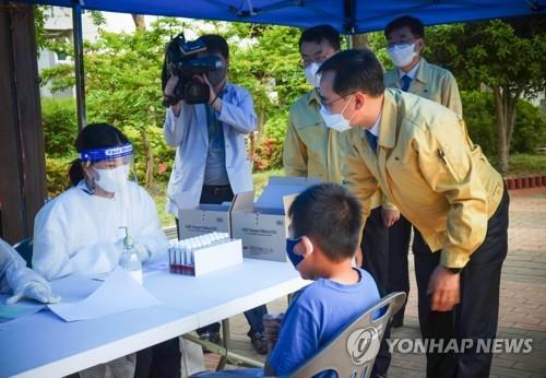 Vice Education Minister Jung Jong-chul (R) visits an elementary school in Ulsan, southeastern South Korea, on May 11, 2021, to monitor the operation of a mobile coronavirus testing center, in this photo provided by his ministry. (PHOTO NOT FOR SALE) (Yonhap)