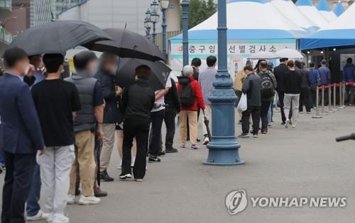 People stand in line to receive coronavirus tests at a makeshift clinic in front of Seoul Station on May 20, 2021. (Yonhap)