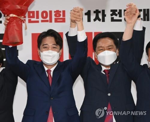 Lee Jun-seok (L) holds up his arms in celebration after winning the chairmanship of the People Power Party in a party convention on June 11, 2021. (Yonhap) 