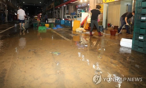 People clean up dirt and mud in Taehwa Market in Ulsan, 414 kilometers southeast of Seoul, on Aug. 24, 2021. (Yonhap)