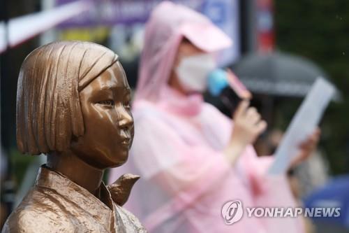 A participant speaks during a protest rally in front of the former site of the Japanese Embassy in Seoul on Aug. 25, 2021, next to a statue symbolizing young Korean girls sexually enslaved by the imperial Japanese army during World War II. (Yonhap)