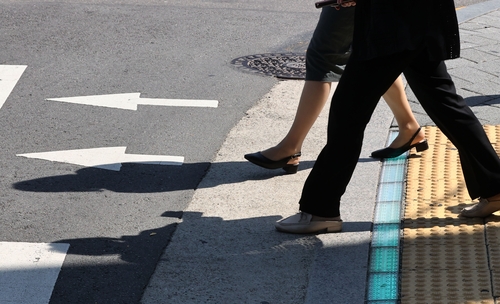 This file photo shows pedestrians walking over in-ground traffic signals.