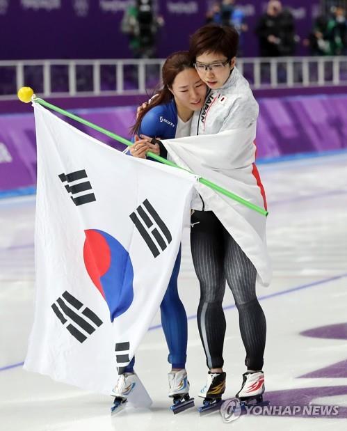In this file photo from Feb. 18, 2018, Lee Sang-hwa of South Korea (L) and Nao Kodaira of Japan embrace each other after winning silver and gold medals in the women's 500m speed skating race at the PyeongChang Winter Olympics at Gangneung Oval in Gangneung, some 240 kilometers east of Seoul. (Yonhap)