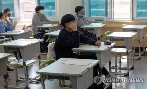 This undated file photo shows students wearing masks as they sit for an exam. (Yonhap)