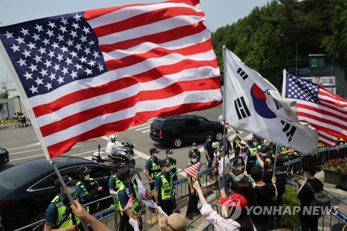 Supporters wave South Korean and U.S. national flags in front of a hotel in Seoul on May 21, 2022, as U.S. President Joe Biden leaves for the presidential office to hold a summit with President Yoon Suk-yeol. (Yonhap)