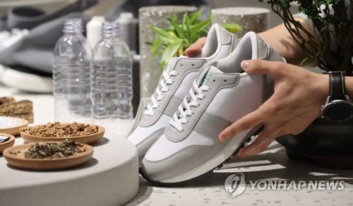In this file photo taken on Oct. 6, 2021, an official shows shoes made with single-use plastics bottles. (Yonhap)