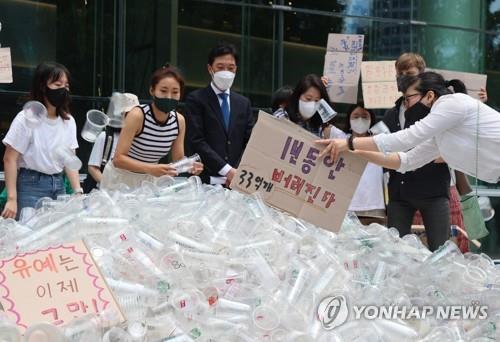 Activists hold a press conference calling for the implementation of the deposit-refund scheme for takeaway cups in central Seoul in front of a mountain of disposable plastic cups on June 10, 2022. (Yonhap) 