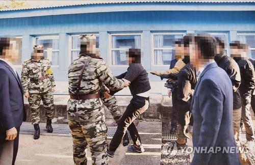This photo, provided by the Ministry of Unification on July 12, 2022, shows a North Korean fishermen, who was captured near the eastern inter-Korean sea border, resisting as he is handed over to North Korean authorities in the inter-Korean truce village of Panmunjom in November 2019. (PHOTO NOT FOR SALE) (Yonhap)