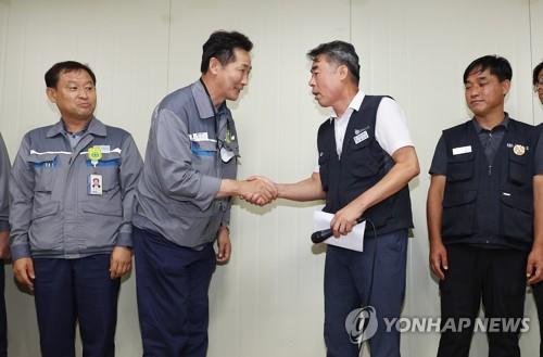 Labor and management representatives shake hands at the Daewoo Shipbuilding & Marine Engineering Co. shipyard on southeastern South Korean coast on July 22, 2022, after reaching an agreement to end a 51-day strike by the shipyard's subcontract workers. (Yonhap)