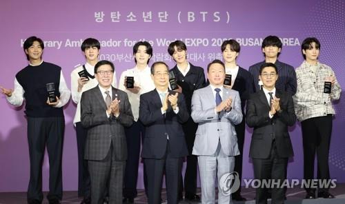In this file photo, Prime Minister Han Duck-soo (2nd from L, front row) poses for a photo with K-pop sensation BTS (back row) and SK Group Chairman Chey Tae-won (2nd from R, front row) during a ceremony to appoint the septet as the promotional ambassador to host the 2030 World Expo in the southern port city of Busan at Hybe in Seoul on July 19, 2022. (Yonhap)