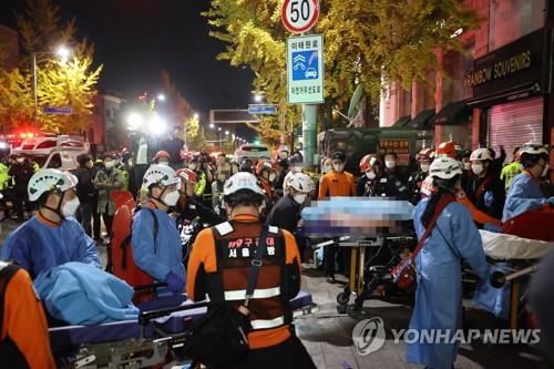 Rescuers move patients on Oct. 30, 2022, in Seoul's Itaewon district after a stampede during Halloween parties killed 120 people. (Yonhap)