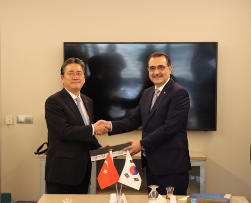 This photo, provided by South Korea's Korea Electric Power Corp. (KEPCO) on Jan. 31, 2023, shows its chief Cheong Seung-il shaking hands with Turkey's energy minister, Fatih Donmez, after submitting a preliminary proposal to take part in a project to build four nuclear power plants in the European country. (PHOTO NOT FOR SALE) (Yonhap)
