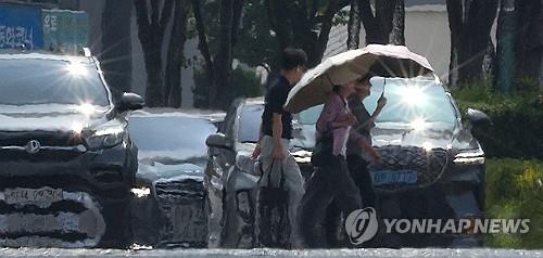 People walk on a shimmering road in the southeastern city of Daegu amid sweltering heat on Aug. 5, 2024. (Yonhap)