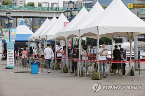 Des citoyens font la queue avant de se soumettre à un test de dépistage du nouveau coronavirus (Covid-19) dans le centre installé sur la place de la gare de Séoul, le dimanche 8 août 2021. 