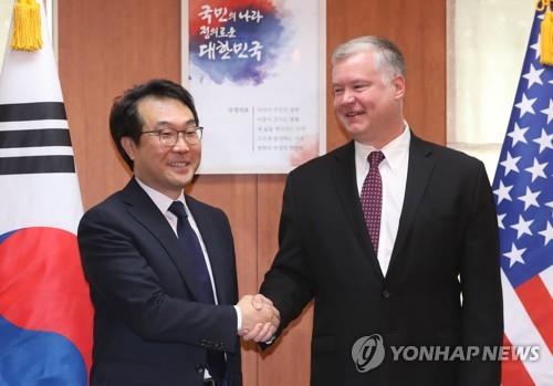 李度勲・朝鮮半島平和交渉本部長（左）と握手するビーガン氏＝１１日、ソウル（聯合ニュース）