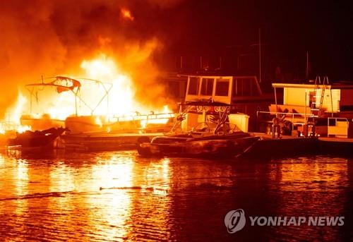 19일(현지시간) 미 캘리포니아 베리예사 호수에 정박한 배들이 불에 타고 있다. [AFP=연합뉴스]