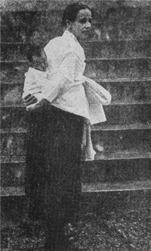 흰 저고리 검정 치마 차림으로 아기를 업고 있는 셰핑 선교사.