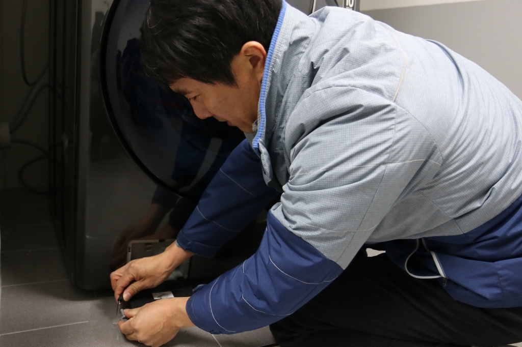 삼성전자서비스 수리 엔지니어가 세탁기 하단 배수펌프의 고인물을 제거하는 모습[삼성전자서비스 제공. 재판매 및 DB 금지]
