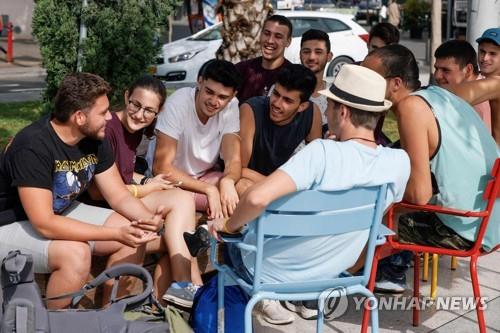 텔아비브 거리에 마스크를 벗은 채 다닥다닥 붙어 앉은 젊은이들 