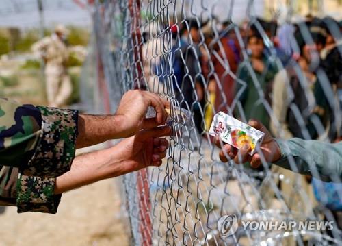 이란-아프간 접경지역 난민 캠프에서 오렌지쥬스를 난민에게 건네는 이란군 [AFP=연합뉴스]