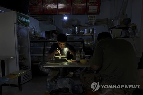 정전사태에 휴대전화 불빛으로 식사하는 중국식당