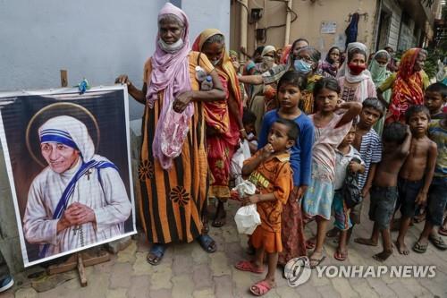  인도 콜카타에서 마더 테레사 초상 옆에 서 있는 주민.