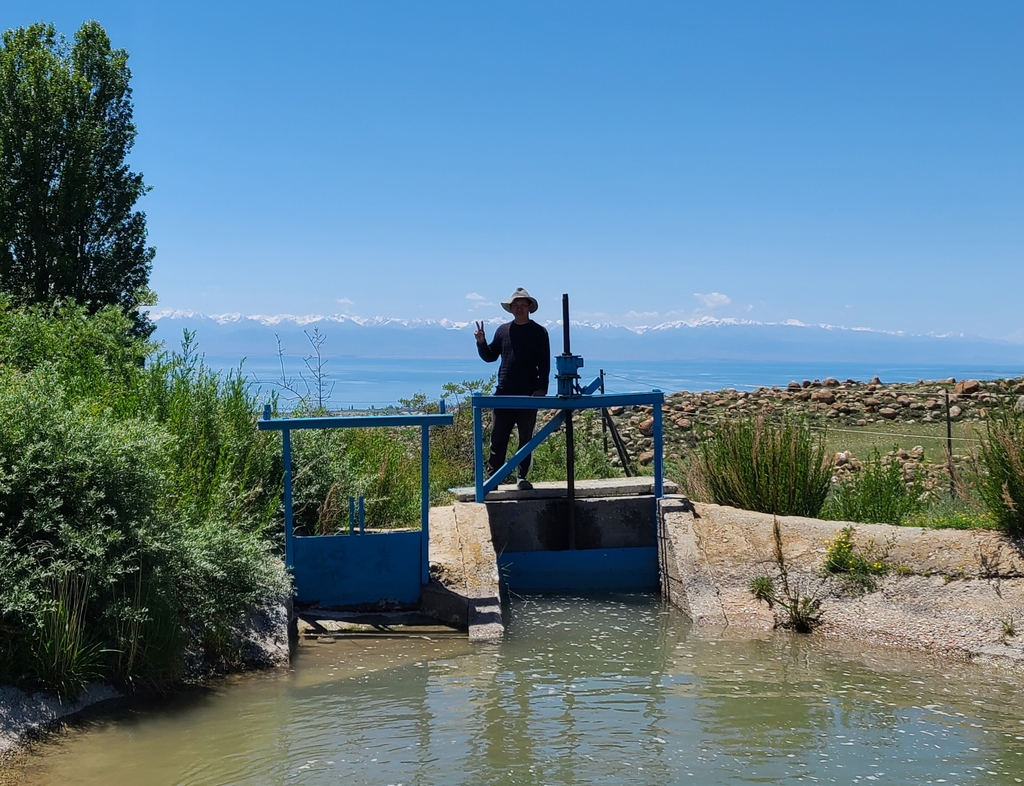 (이식쿨[키르기스스탄]=연합뉴스) 홍규빈 기자 = 8일(현지시간) 총사르오이 마을 주민이 수량 조절기 위에서 브이 표시를 하는 모습. 2022.6.8rbqls@yna.co.kr