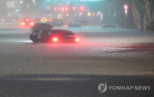 지난 8일 밤 서울 강남구 대치역 인근 도로에서 차량이 침수되자 운전자가 대피하고 있다. [연합뉴스 자료사진]